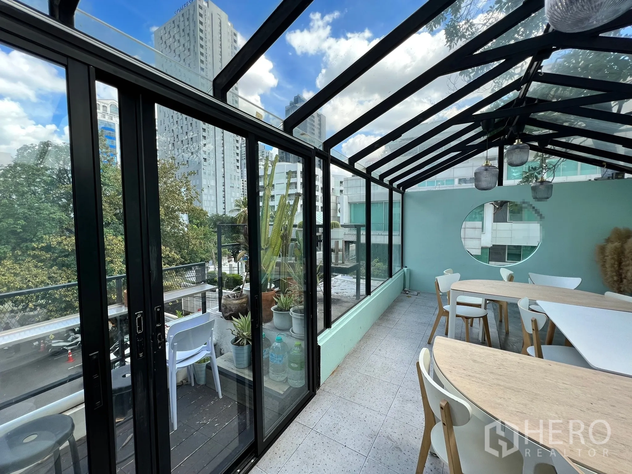 零售空间 出租在Watthana, Bangkok - 日照充足的玻璃房空间，推拉门通向阳台，城市景观与弧形桌椅。