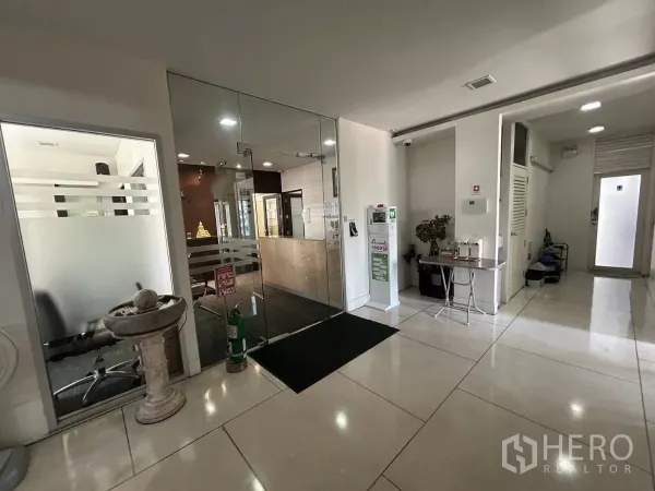 สำนักงาน ให้เช่า - โถงทางเข้าอาคารพร้อมประตูกระจกเข้าสำนักงาน พื้นกระเบื้องและเคาน์เตอร์ต้อนรับ