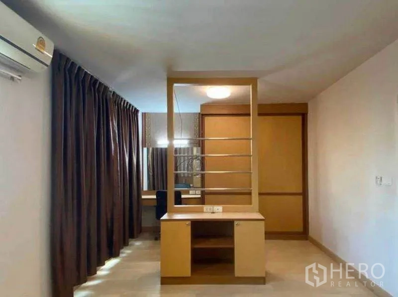Townhouse for rent in Suan Luang, Bangkok - Spacious bedroom with partition shelving, built-in cabinetry and air conditioning.