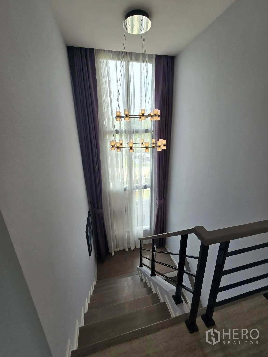 Semi-detached House for rent in Bang Phli, Samut Prakan - Staircase with wooden steps, black handrail, tall window and chandelier.
