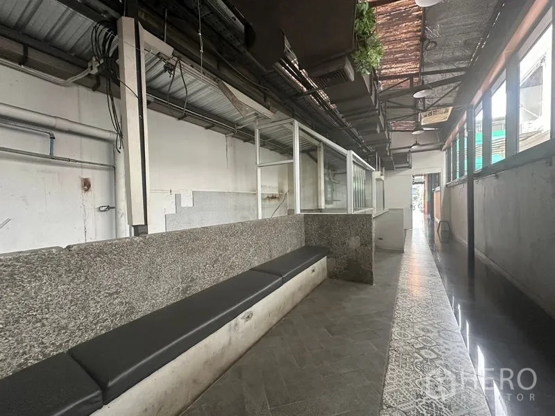 零售空间 出租在Bang Rak, Bangkok - 工业风零售走廊，花岗岩吧台、玻璃隔断、长椅与外露天花。