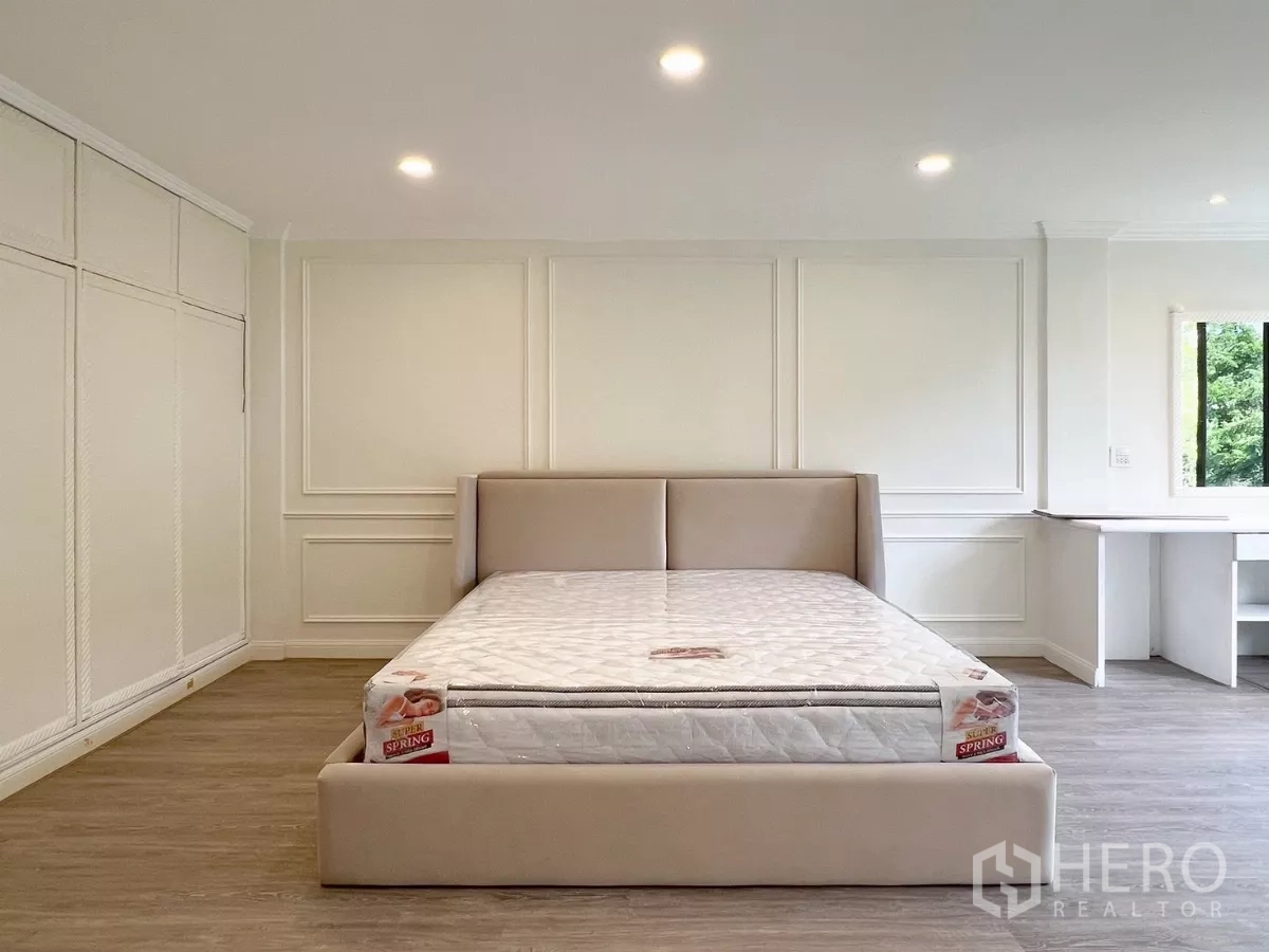 Townhouse for rent - Large bedroom with paneled walls, built-in desk, wardrobe and window views.