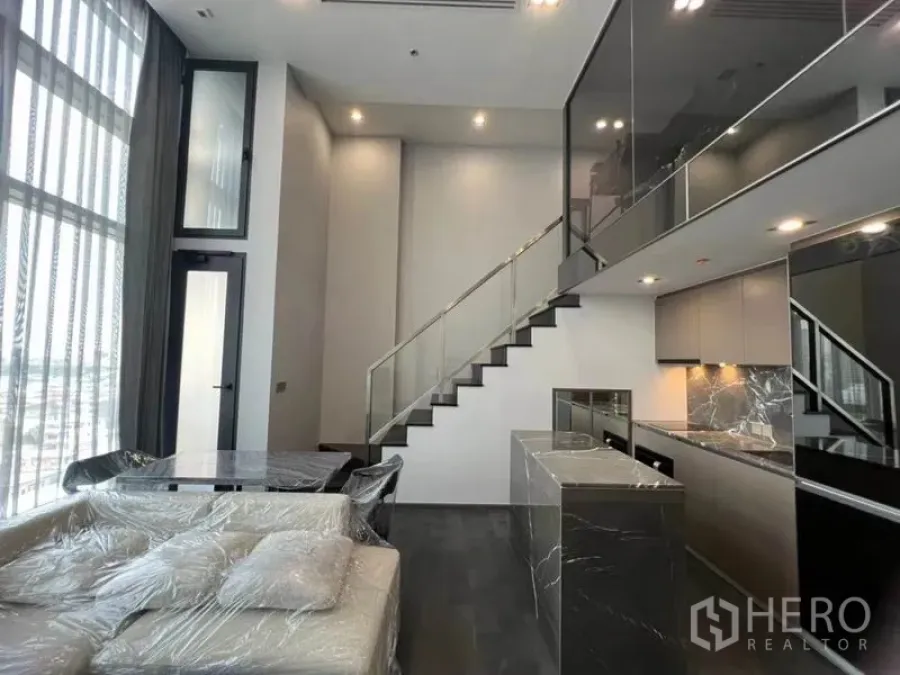 公寓 出租在Ratchathewi, Bangkok - 采光充足的起居餐区，沙发、中岛厨房与通往阁楼的楼梯。