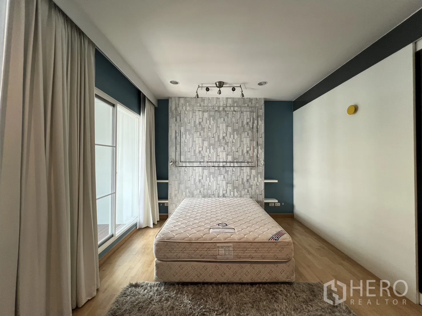 Townhouse for rent in Wang Thonglang, Bangkok - Master bedroom with bed, wood floor and sliding door to balcony.