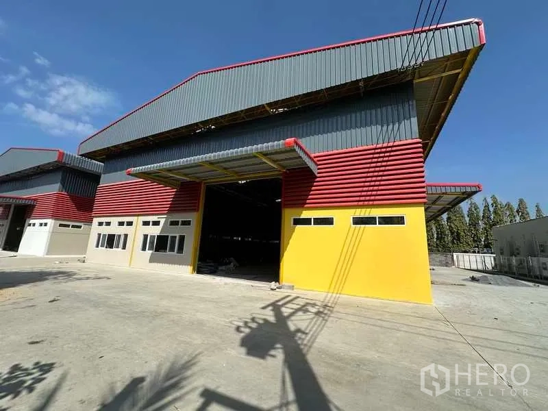 货栈 出租在Lam Luk Ka, Pathum Thani - 现代仓库正立面，金属板外墙，高斜屋顶，卡车通行便捷的车道。