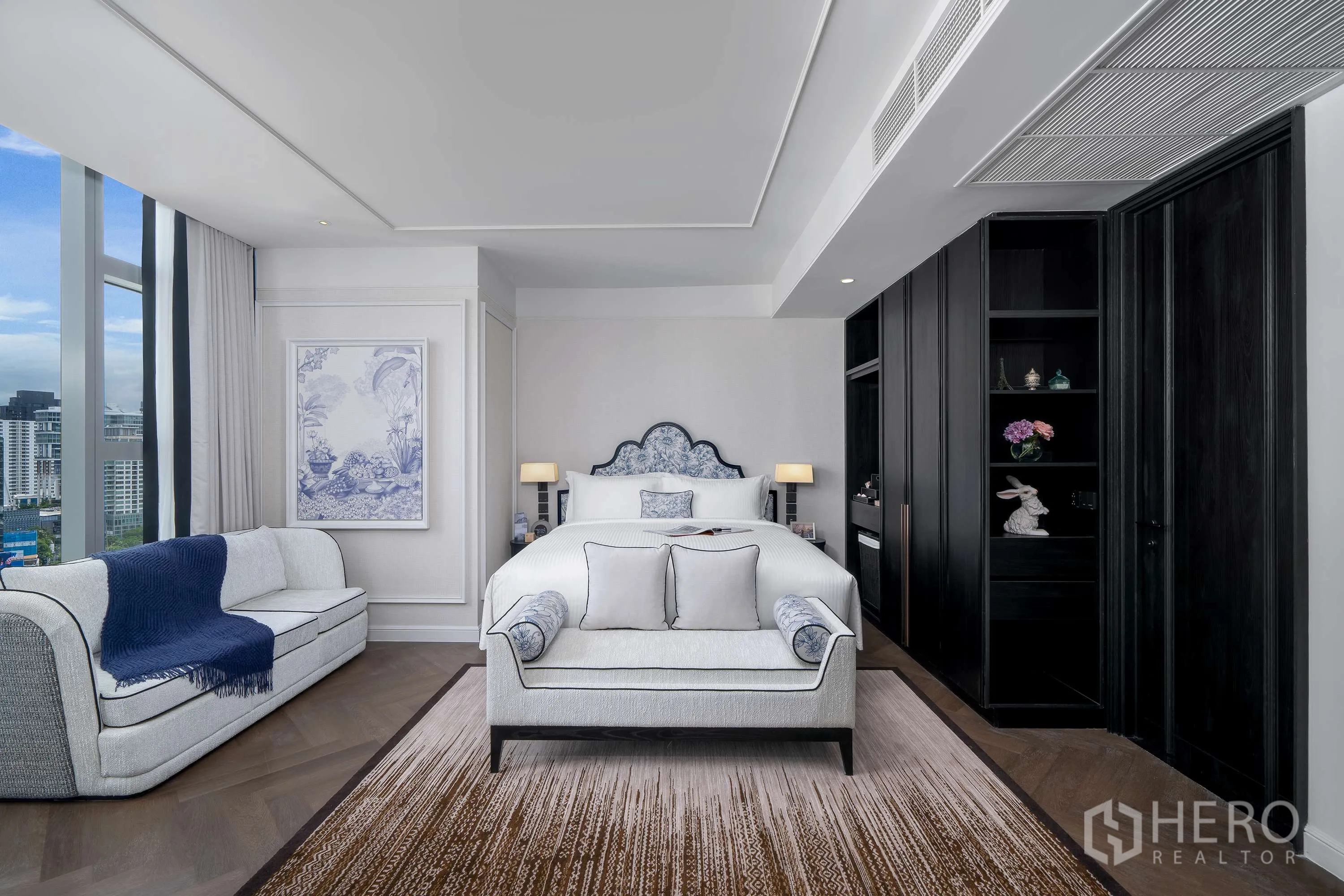 Condominium for rent in Khlong Toei, Bangkok - Bedroom with upholstered headboard, bench, sofa, and built-in shelving near the windows.