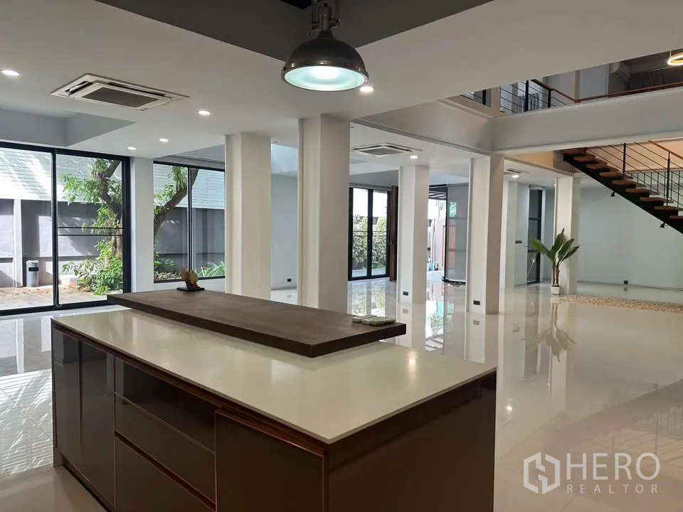 Detached House for sale in Watthana, Bangkok - Close-up of a kitchen island in a bright open-plan area with staircase.