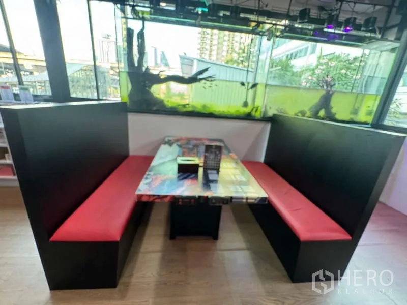 零售空间 出租在Ratchathewi, Bangkok - 设有红色卡座与桌子的用餐区，旁边为观赏鱼缸。