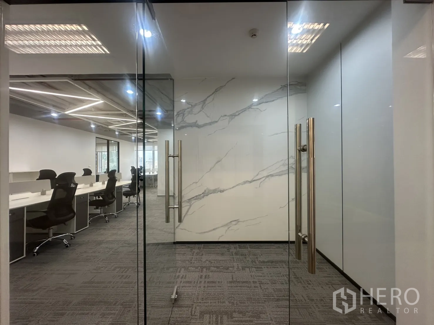 办公室 for rent in Pathum Wan, Bangkok - 双开玻璃门通向办公室，可见仿大理石墙与天花灯光。