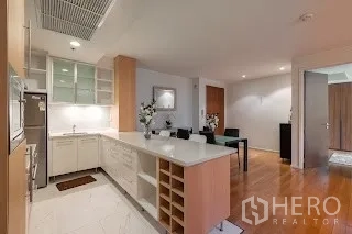 Condominium for rent in Bang Rak, Bangkok - U-shaped kitchen with white countertops, island breakfast bar and ample storage.