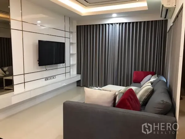 Detached House for rent in Bang Phli, Samut Prakan - Bright living room with built-in TV wall, gray blackout curtains, recessed lighting and L-shaped sofa.