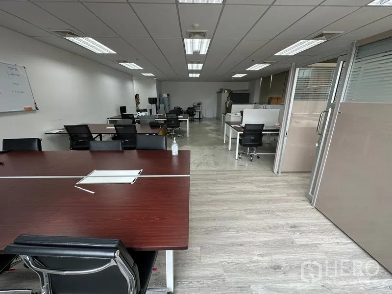 Office Space for rent in Khlong Toei, Bangkok - Open-plan office with multiple workstations, glass partitions and wood-look floors under bright ceiling lights.