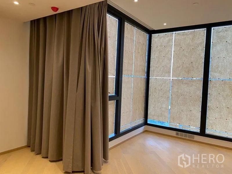 คอนโด ขายในDin Daeng, Bangkok - พื้นที่นั่งเล่นมุมกระจกบานใหญ่ ผ้าม่านทึบ และพื้นไม้โทนอุ่น