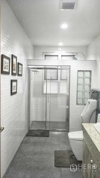 Home Office for sale in Phasi Charoen, Bangkok - Bright bathroom with glass-enclosed shower, white tiles and modern fixtures.