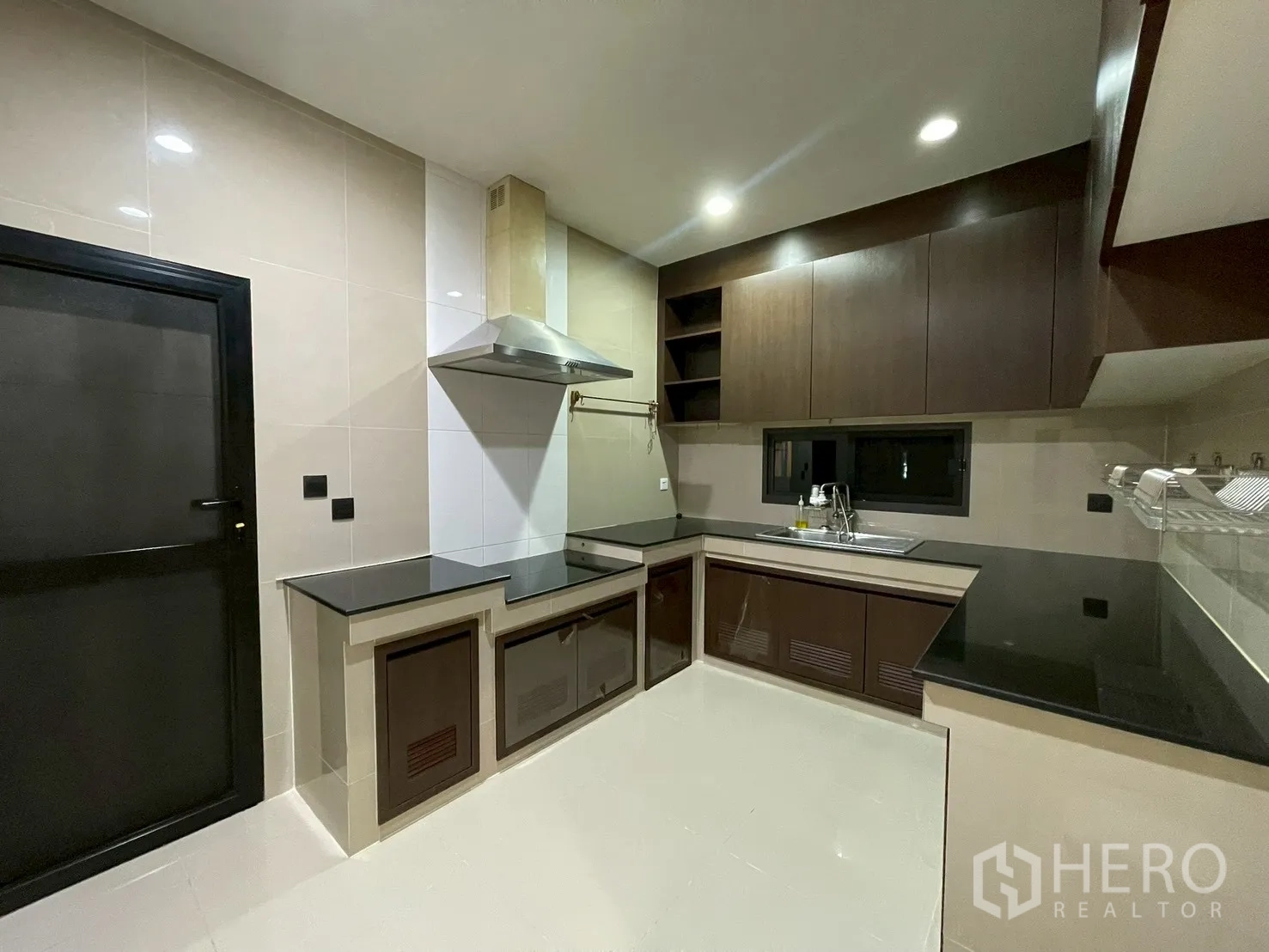 Detached House for rent in Bang Kapi, Bangkok - Fitted kitchen with dark wood cabinets, range hood, and black countertops.