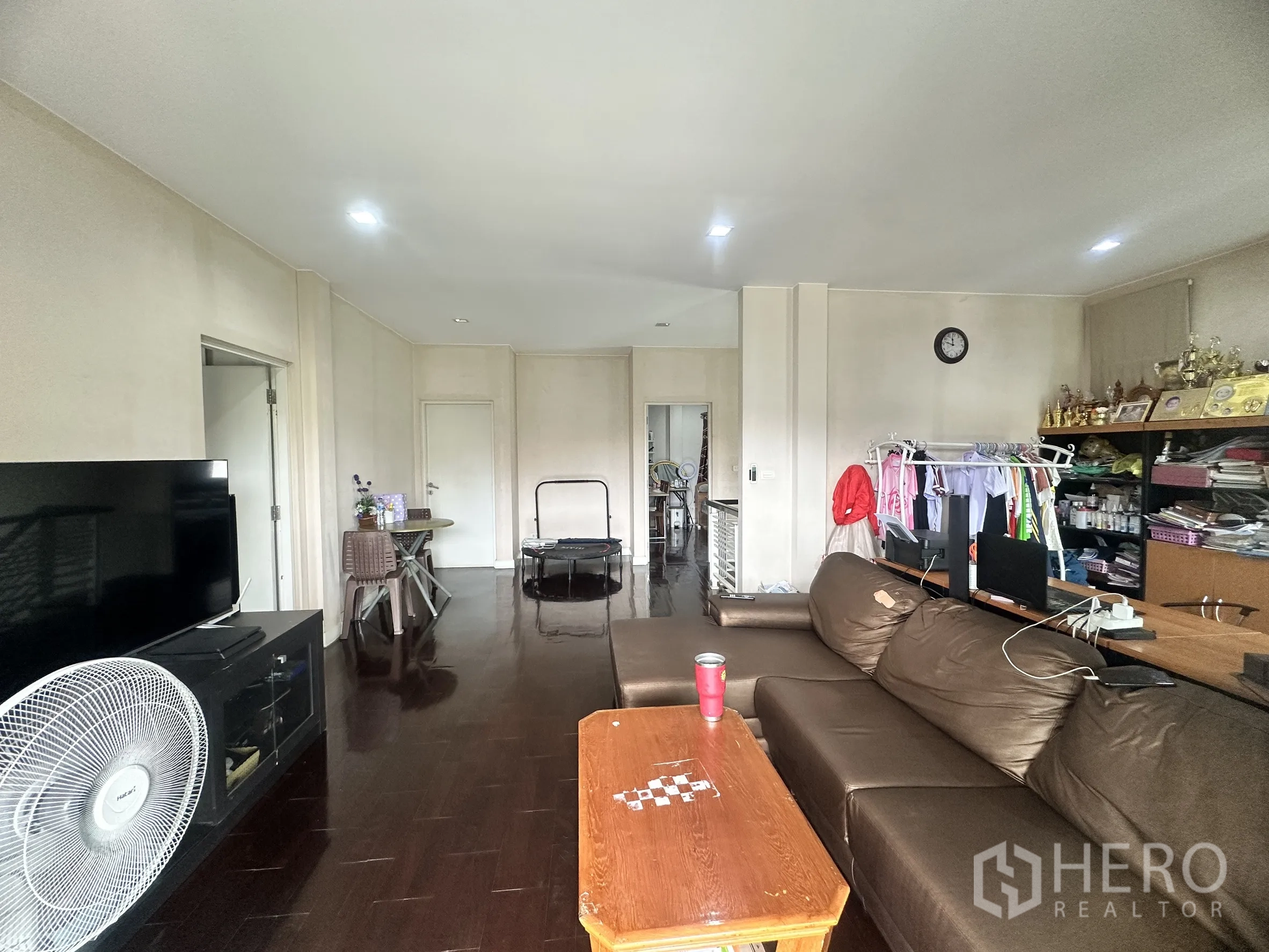 Detached House for sale in Pak Kret, Nonthaburi - Living area with brown sectional sofa, TV console, and wood floors.
