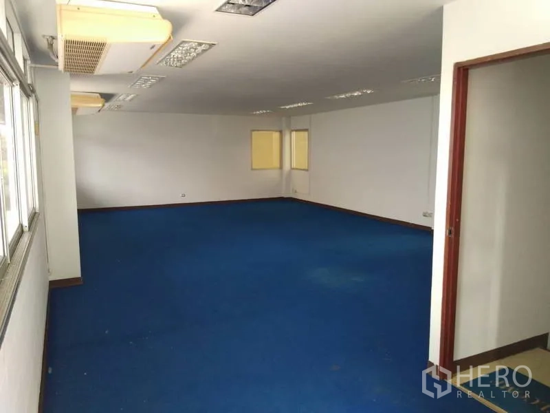 Warehouse for rent in Bang Phli, Samut Prakan - Second-floor office overlooking the warehouse with blue carpet and a row of windows.