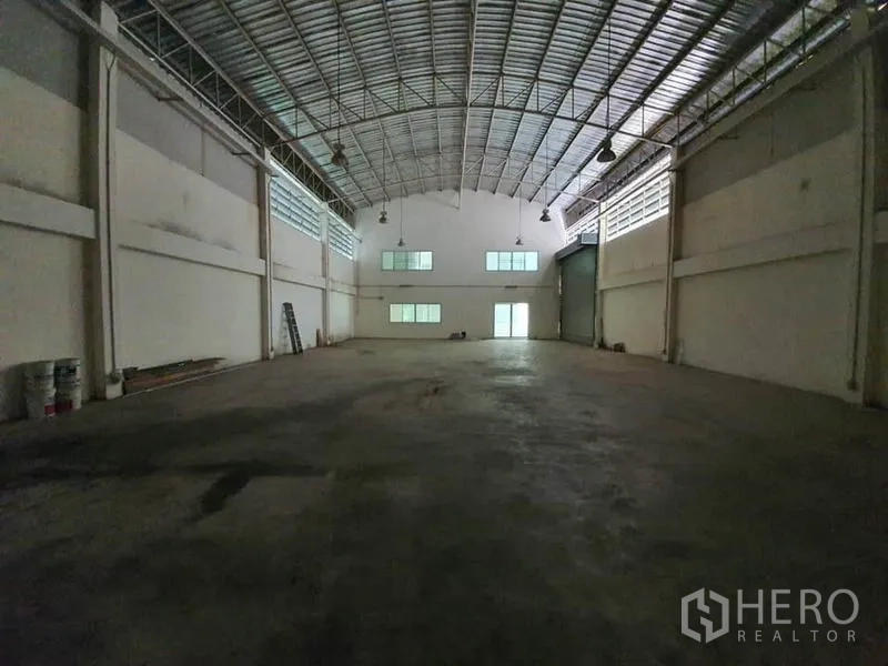 Factory for rent in Lam Luk Ka, Pathum Thani - Open factory floor with column-free space, skylights, hanging lights and rear loading access.