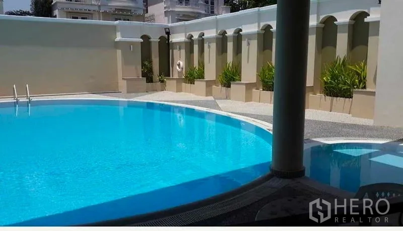 Townhouse for rent or sale in Bang Kho Laem, Bangkok - Estate swimming pool with curved edge and landscaped privacy wall.