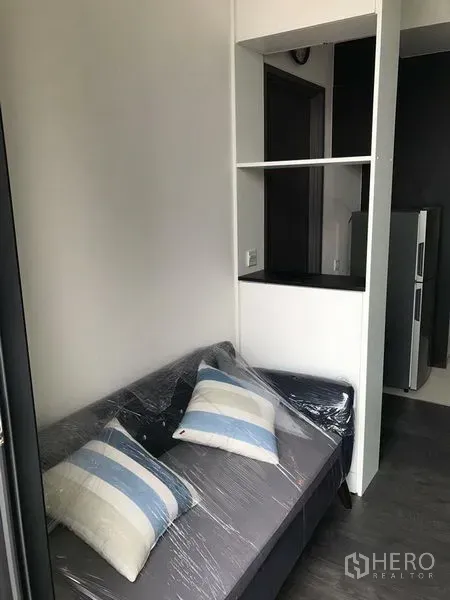 คอนโด ให้เช่าในWatthana, Bangkok - มุมนั่งเล่นพร้อมโซฟาหุ้มพลาสติกและชั้นวางของแบบเปิดข้างทางเข้า