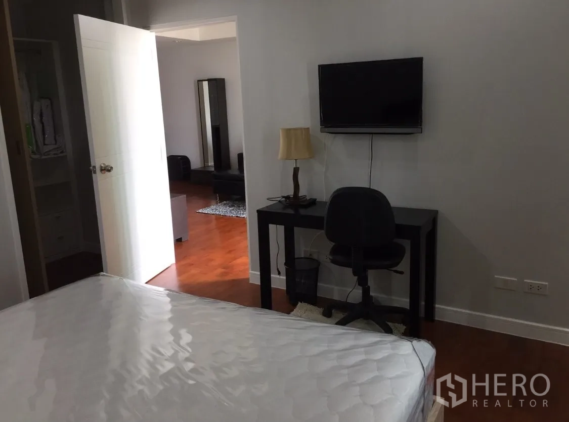 คอนโด ให้เช่าในKhlong Toei, Bangkok - ห้องนอนพร้อมพื้นไม้ โต๊ะทำงาน และทีวีติดผนัง มองเชื่อมสู่พื้นที่นั่งเล่น