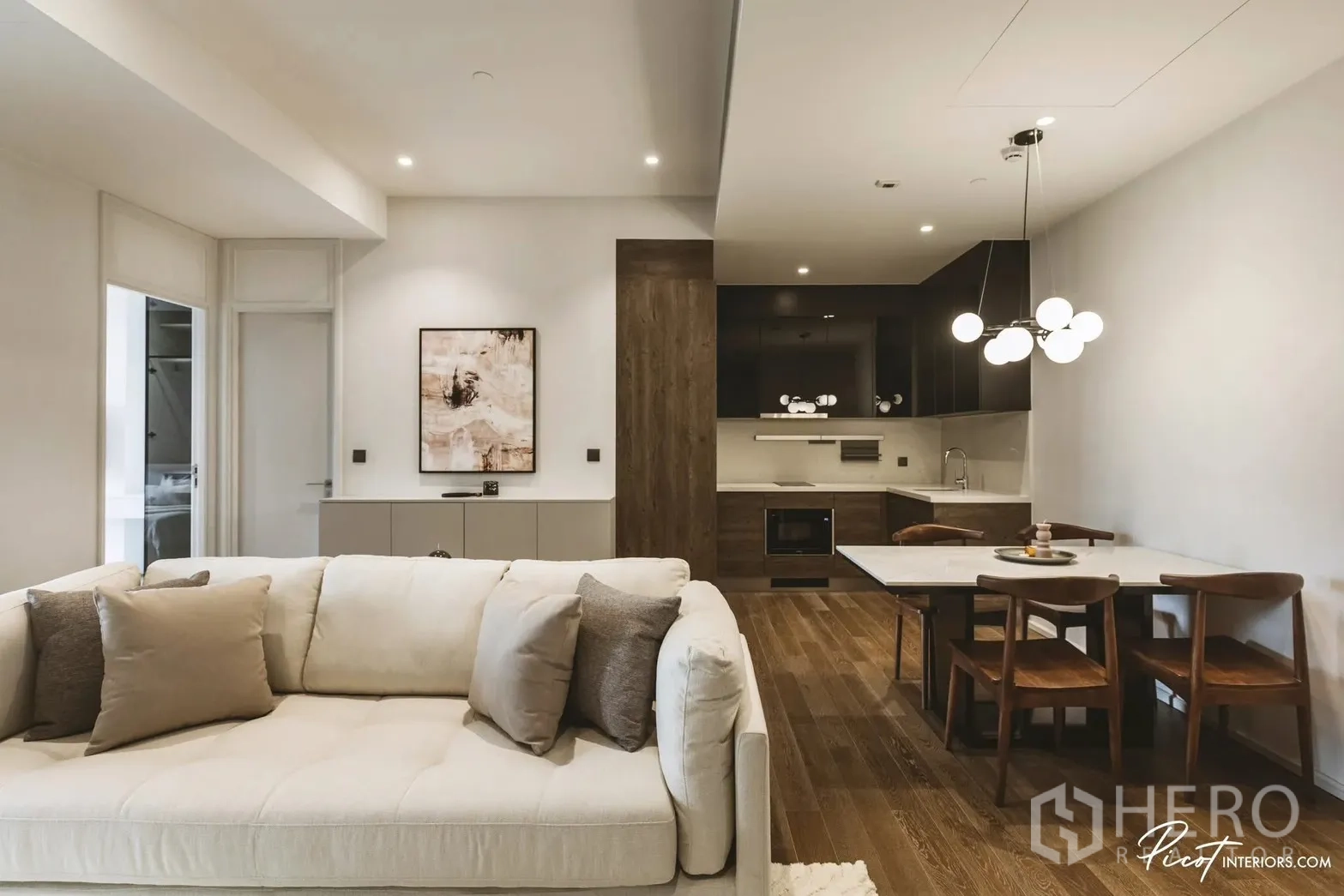 Condominium for rent in Pathum Wan, Bangkok - Open-plan space with dining table, pendant lighting, and modern kitchen with dark cabinetry and oven.