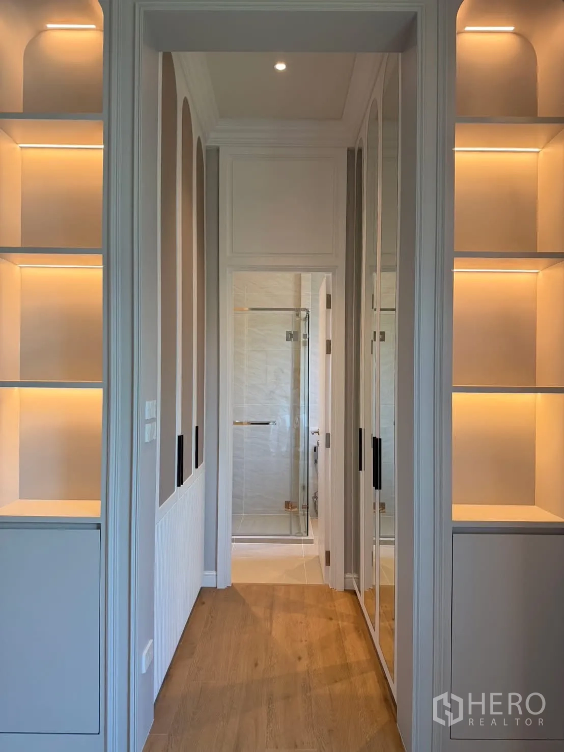 Detached House for rent in Saphan Sung, Bangkok - Walk-in closet hallway with illuminated shelves and mirrored doors leading to a glass shower.