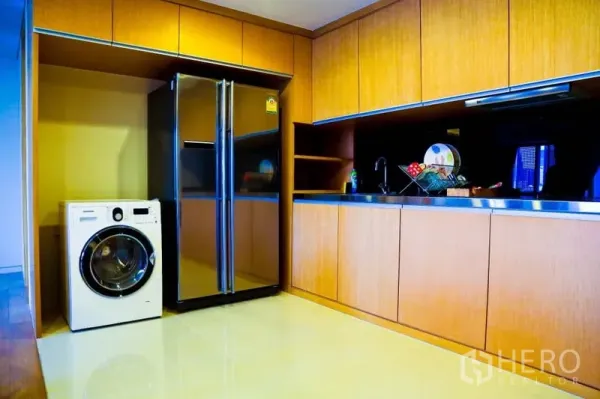 Condominium for rent in Watthana, Bangkok - Sleek kitchen with full-height wood cabinetry, double-door fridge and washing machine.