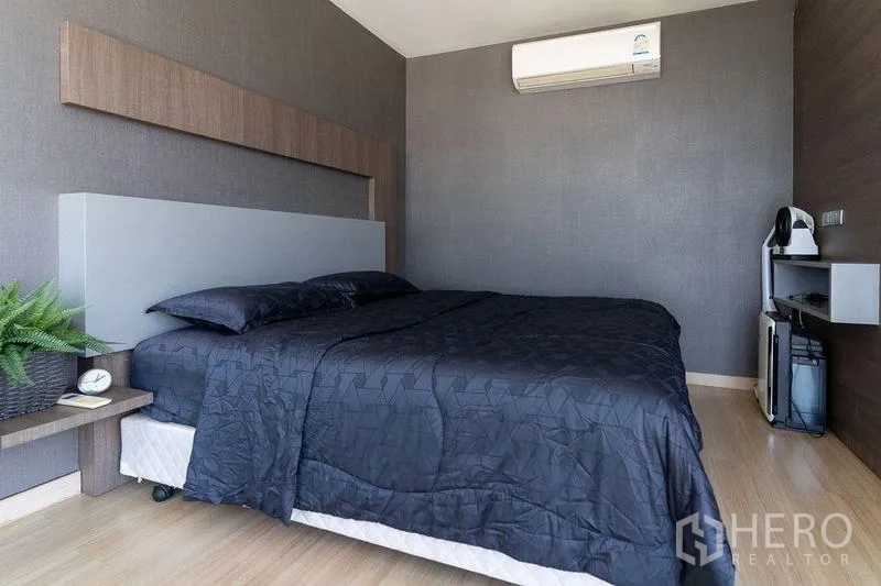 Condominium for rent - Cozy bedroom with double bed, wood accents and wall-mounted air conditioner.