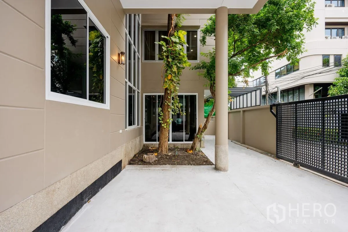 Detached House for rent or sale in Chatuchak, Bangkok - Ground-level patio with mature trees, sliding doors, and privacy fence.