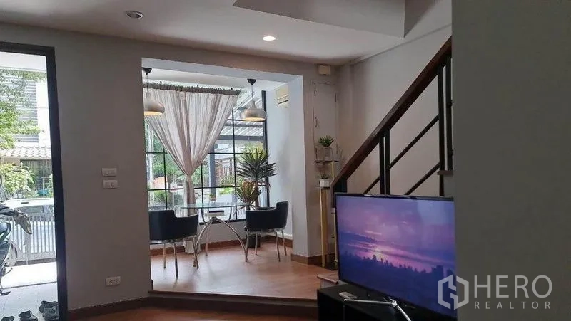 Townhouse for sale in Suan Luang, Bangkok - Open-plan living space facing front bay-window dining nook and staircase with TV.