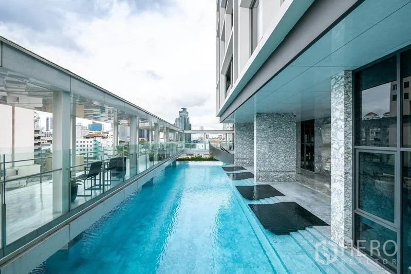 Condominium for rent or sale in Khlong Toei, Bangkok - Elevated lap pool with glass balustrade and city skyline views at the condo.
