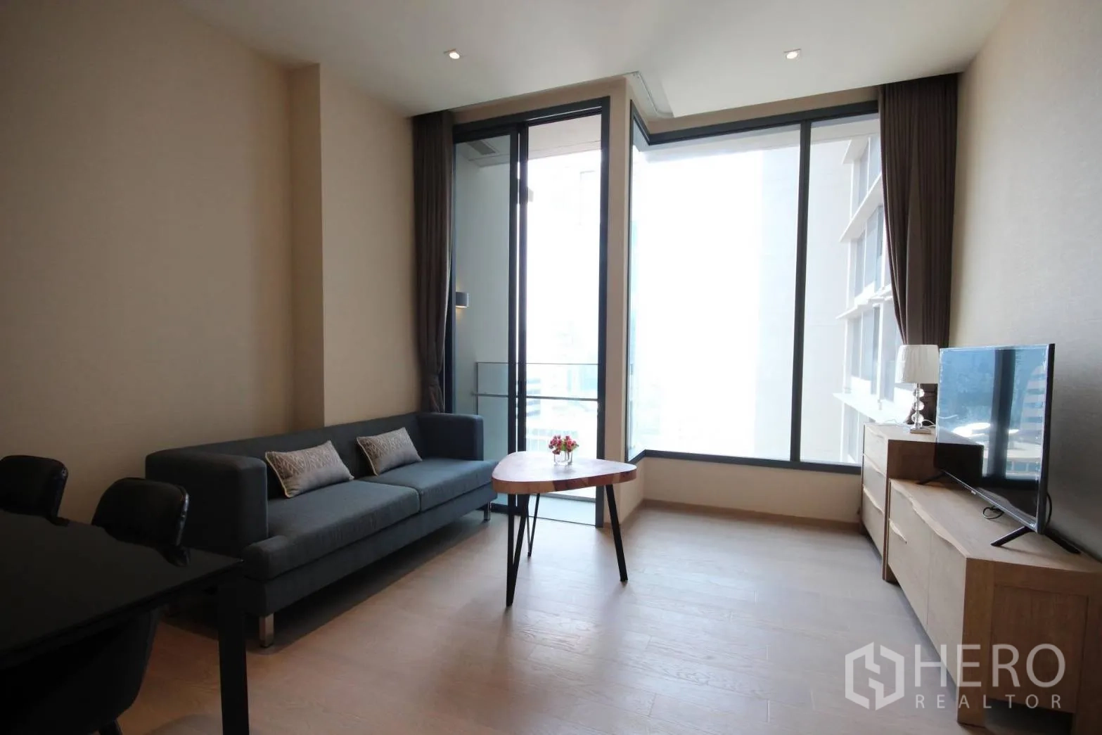 Condominium for rent in Watthana, Bangkok - Bright living room with floor-to-ceiling windows, sofa, TV console and a small balcony.