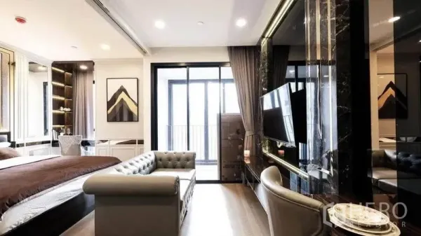 Condominium for rent in Bang Rak, Bangkok - Open-plan 34 sqm one-bedroom layout with gray tufted sofa, marble TV wall and sliding glass doors to the balcony.