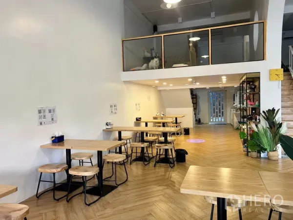 店屋 出租在Phra Khanong, Bangkok - 明亮的店屋用餐区，挑高空间，夹层和人字形木地板。