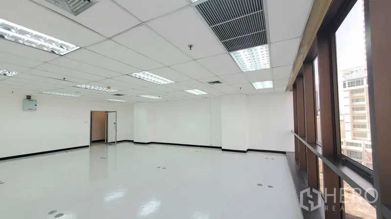 办公空间 出租在Watthana, Bangkok - 开放办公空间，长排窗户、荧光灯与空调出风口，旁侧有通往内室的门。