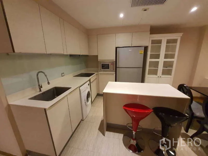 公寓 出售在Watthana, Bangkok - 厨房一角展示嵌入式洗衣机、双水槽与充足柜体。
