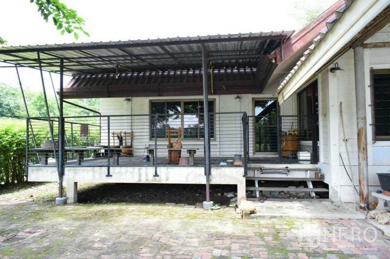 Land for sale in Khlong Luang, Pathum Thani - Elevated single-storey house with covered terrace and brick patio on spacious Khlong Luang land.