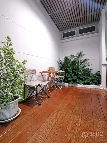 Home Office for rent or sale - Covered terrace with wood flooring, lush greenery and folding chairs.