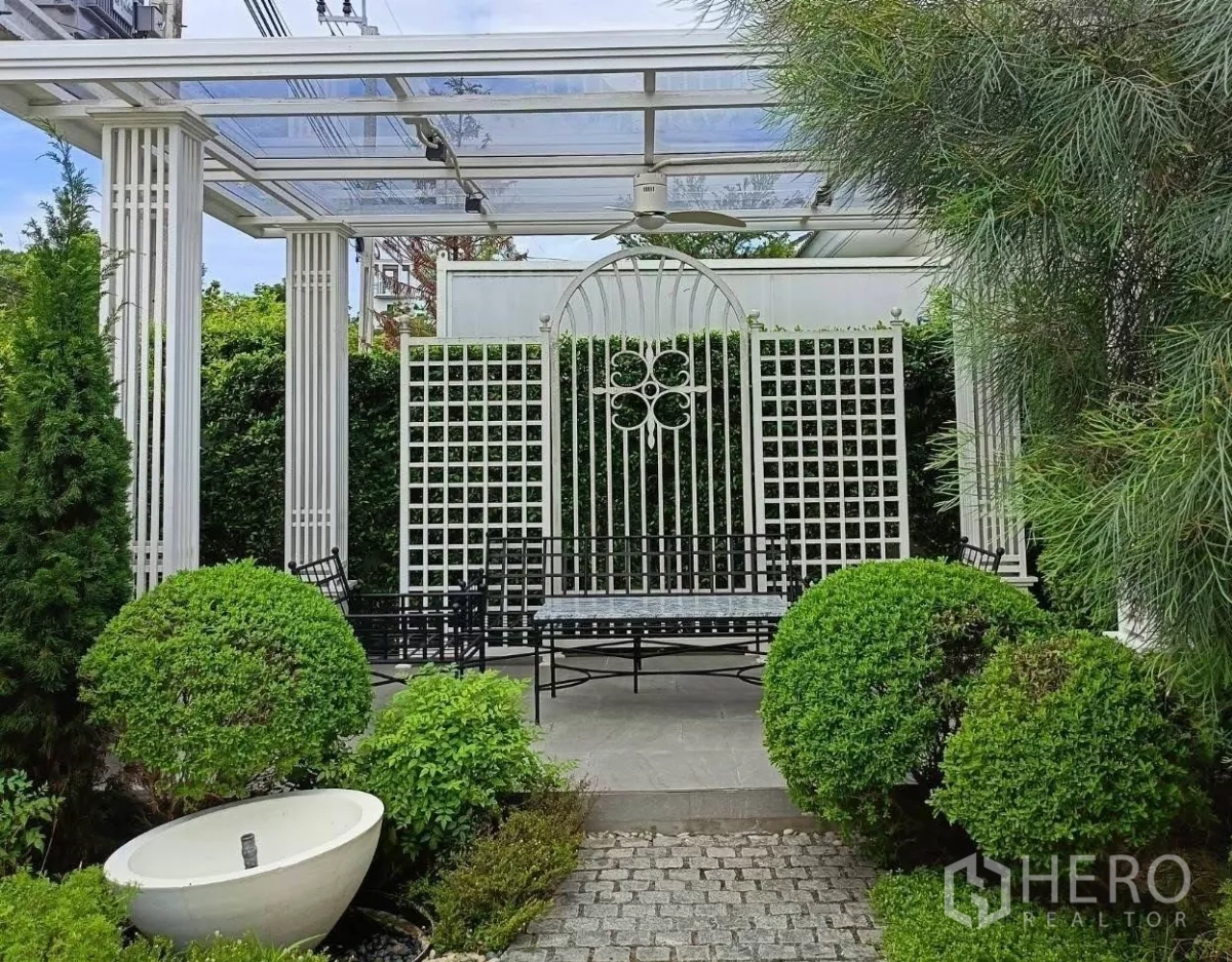 Detached House for rent in Bang Phli, Samut Prakan - Backyard pergola patio with lattice screens, benches and lush landscaped shrubs.