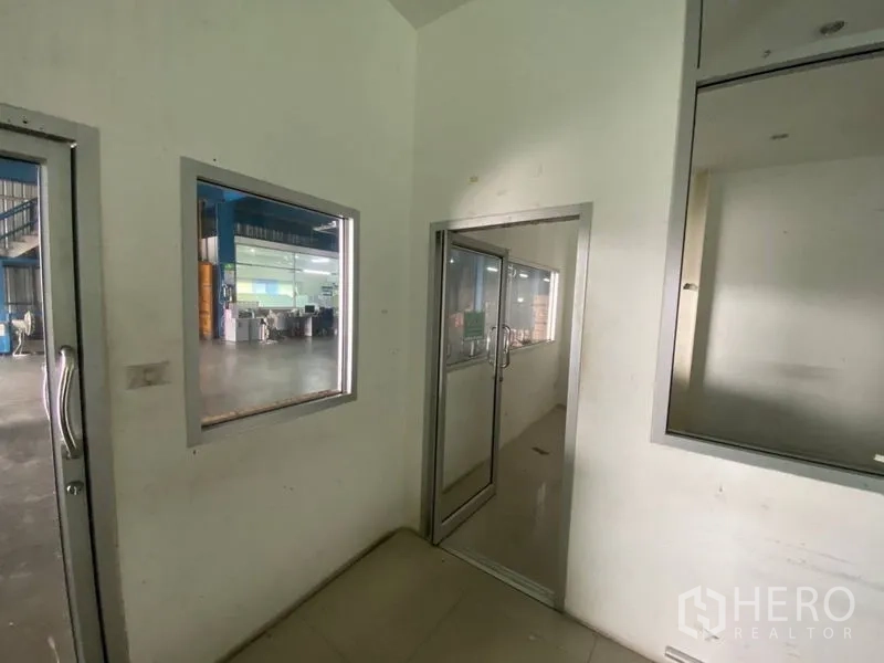 Factory for rent or sale in Lam Luk Ka, Pathum Thani - Internal corridor with windows and doors overlooking the production area.