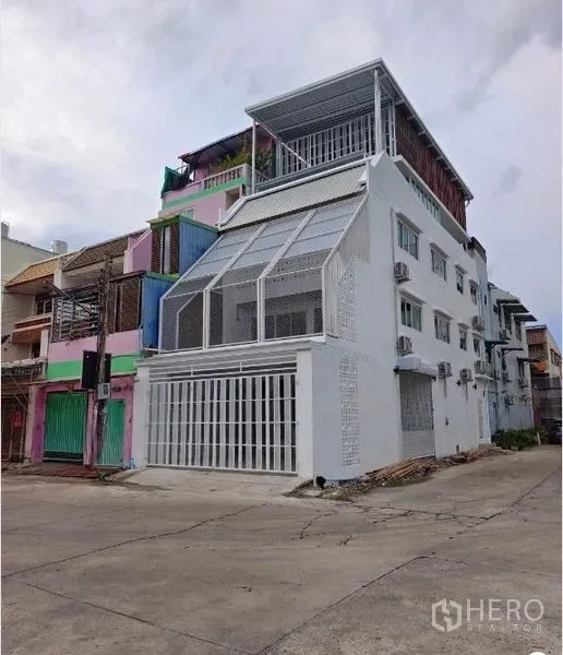 Townhouse for sale in Bang Phlat, Bangkok - Street view of the white corner townhouse with rooftop terrace and multiple AC units.