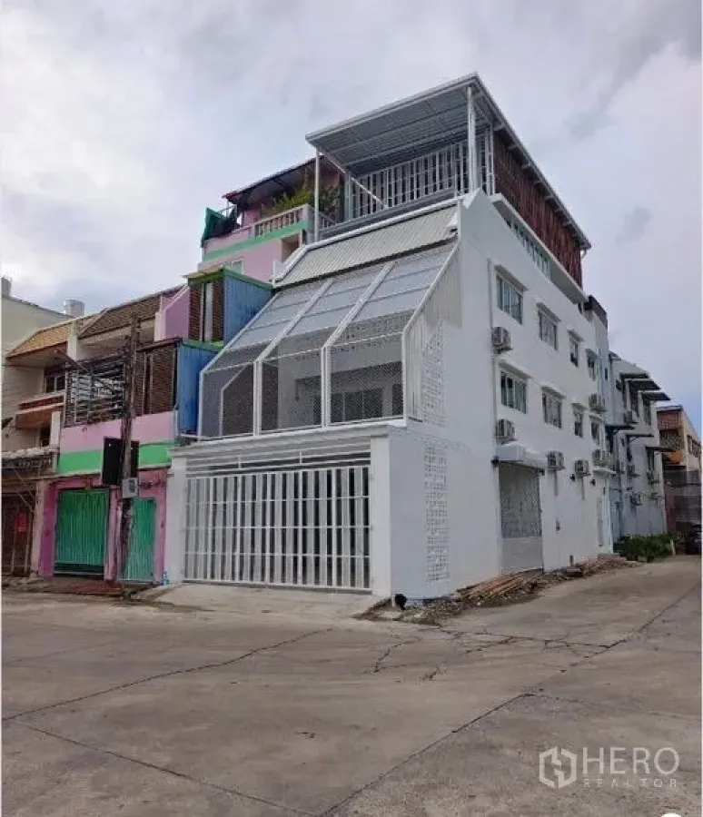 Townhouse for sale in Bang Phlat, Bangkok - Street view of the white corner townhouse with rooftop terrace and multiple AC units.