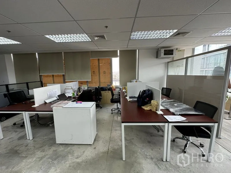 Office Space for rent in Khlong Toei, Bangkok - Work area with partitioned desks, rolling chairs and window blinds under fluorescent lighting.