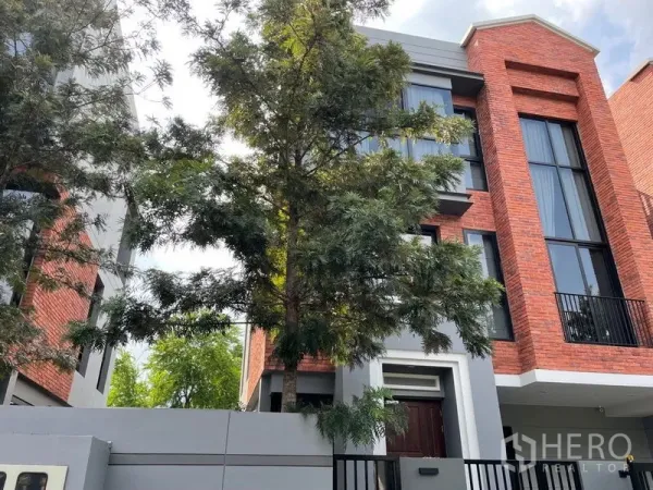联排别墅 出售在Lat Phrao, Bangkok - 现代红砖外立面的多层联排别墅，落地窗与树荫门前。