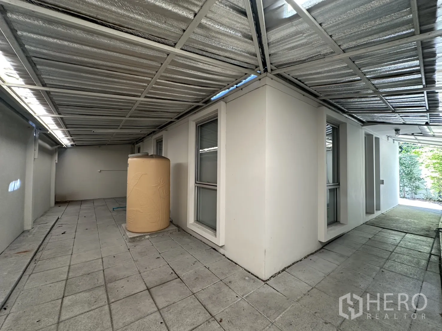 Home Office for rent in Phra Khanong, Bangkok - Covered rear terrace with a metal roof, windows, and a water tank.