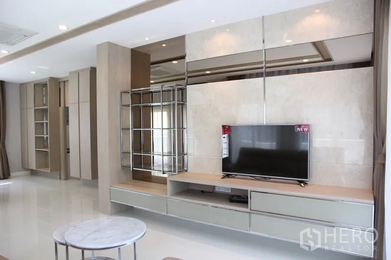 独立式住宅 出租在Bang Na, Bangkok - 采光充足的客厅，镜面背景墙配内置电视柜与展示格