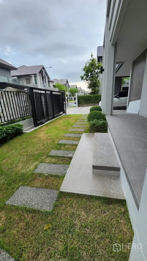 บ้าน ให้เช่าหรือขายในBueng Kum, Bangkok - สวนหน้าบ้าน สนามหญ้า ทางเดินแผ่นทาง และรั้วเหล็กสีดำ