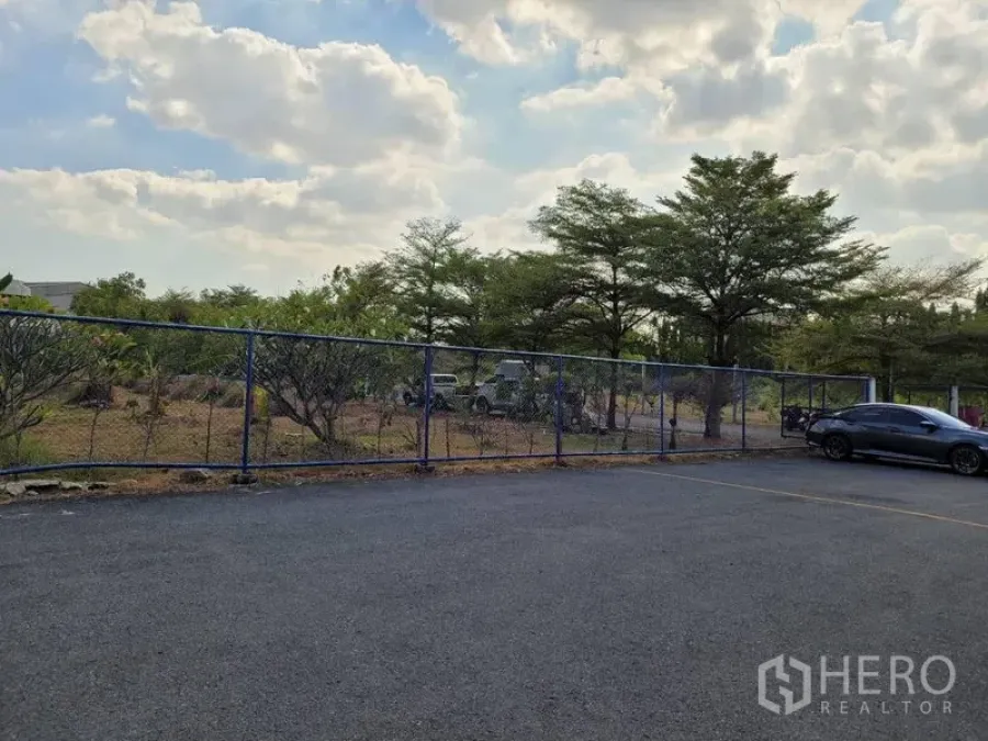 คลังสินค้า ให้เช่าในPhra Khanong, Bangkok - ลานจอดรถพื้นยางมะตอยพร้อมรั้วลวดตาข่ายและต้นไม้รายรอบ ของโกดังในเขตพระโขนง กรุงเทพฯ