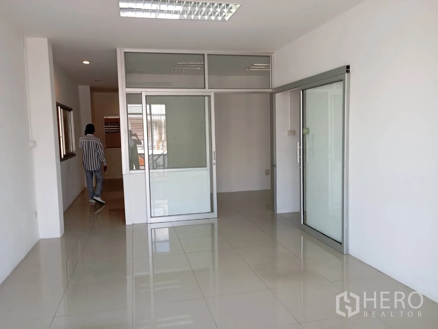 Warehouse for rent in Bang Phli, Samut Prakan - Office area with tiled floor, fluorescent lighting, and sliding glass partitions.